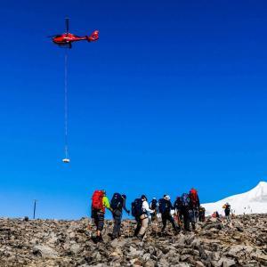 En helikopter flyger över våra besökares vandring på Kebnekaise